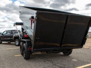 A black trailer with a large metal container on the back.