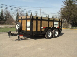 A large trailer with wood sides and a tire rack.