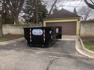 A dumpster truck parked in front of a garage.